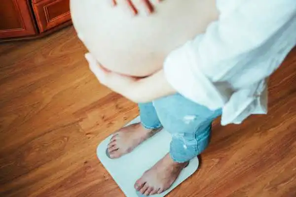 Image of woman weighing herself and experiencing weight gain through pregnancy Wibsey